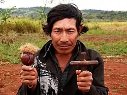 Guarani shaman holding cross and maraca