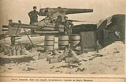 soldier standing in front of a 15 cm caliber gun