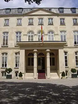Grand building entrance with two columns, carpeted staircase, and wall carvings of Egyptian-style figures