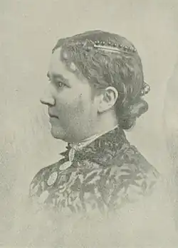 19th-century B&W portrait photo of a woman with her hair in an up-do, wearing a dark, fitted blouse.