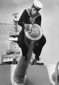 A sailor polishing the tampion of an 8-inch gun on the Australian heavy cruiser, HMAS Australia in the early 1950s.