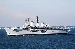 Side view of a small aircraft carrier with a ski-jump ramp underway