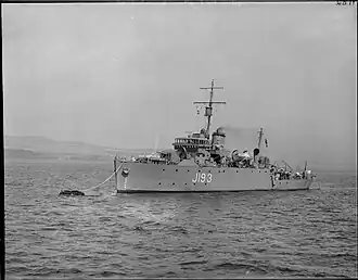 A military ship with the number J193 on its side sailing on a body of water.
