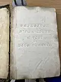 Raised Roman letters embossed onto a page of a book.