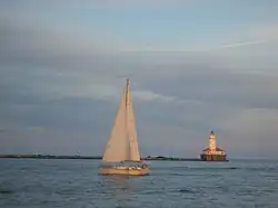Photograph of sailboats passing a lighthouse