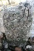 Close up view of the inscription of a rock that does not seem to have been worked on by a stonemason, given its irregular shape and unsmoothed surface.