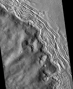 Hecates Tholus ridges, as seen by HiRISE. Ridges are to the west-northwest of Hecates Tholus. It has been proposed that this region was affected by a volcanic eruption that occurred under a 200 meter-thick ice sheet.[13]