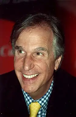 A balding man looks towards his right while smiling.