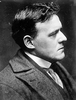 Belloc with short black hair wearing a houndstooth-patterned suit sitting in profile