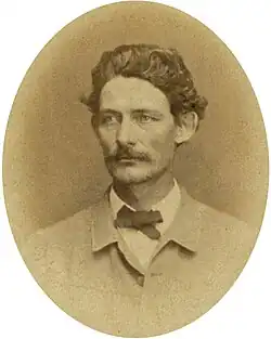 Sepia toned and oval photo shows Hiram B. Granbury with a moustache and thick hair wearing a white shirt and light colored coat.