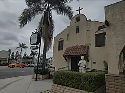 Exterior of a mission-style building with a palm tree in front