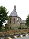 Holy Trinity Church, Lyonsdown Road, New Barnet, London, 1865 by Ewan Christian, showing the strong chancel apse in stock brick with red brick banding[160]