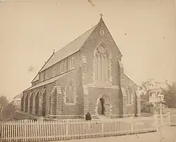 Photograph of a small brick church with a steep roof