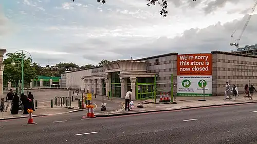 Closed, fenced-off store in stone building with Egyptian Revival lotus-topped columns