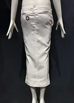 Rear view of a white column skirt whose waistline is low enough to reveal the top of the buttocks