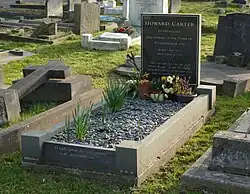 A polished, black granite headstone with freshly planted flowers, among other gravestones