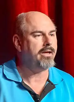 Portrait of a man with a dark mustache and greying goatee.