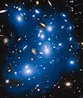 Abell 2744 intracluster light artificially colored in blue. This light come from galaxies that were torn apart long ago by the cluster's gravitational forces. [13]
