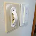A Hue dimmer switch, with a switch guard over the conventional wall light switch to keep it in the ON position