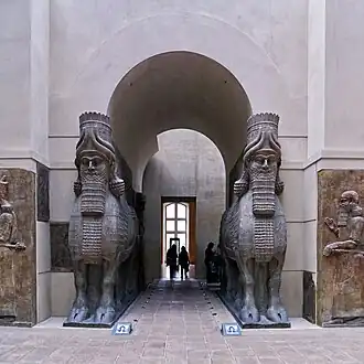 Pair of large stone lamassu sculptures built into an arched doorway, from ancient Assyrian palace, displayed in the Louvre