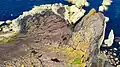 The rugged point, seen from above, shows gently sloping beds of red sandstone above vertical beds of greywacke, forming a classic example of Hutton's Unconformity.