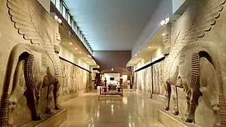 Pair of stone lamassu sculptures with human heads and winged bull bodies displayed in the Iraq Museum