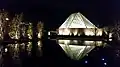 The prayer hall illuminated at night, reflected in one of the ponds of the formal garden