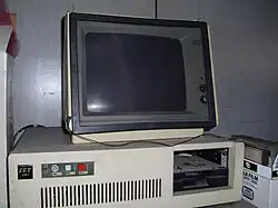 A 1980s white box IBM PC compatible with one full-height 5.25-inch drive bay containing a half-height 5.25-inch floppy drive[a]