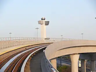JFK Airport's control tower in the background and an AirTrain guideway in the foreground