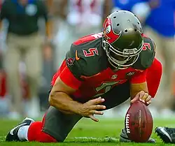 Kneeling to hold a football for the kicker