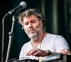 A man wearing headphones uses a digital turntable.