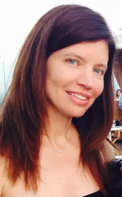 A woman, standing and smiling