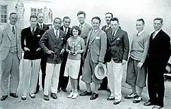 Group photograph showing several men and one woman standing together. They pose closely, facing the camera.