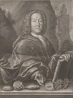 An engraving depicts a man in formal 18th-century attire with curled hair, resting one hand on a large book and the other beside seashells, a fish, and botanical specimens