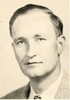 White male with dark hair in a tan suit