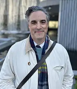 A man staring directly forward. He is wearing a white jacket.