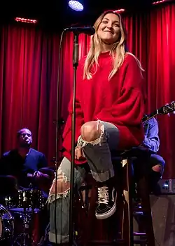 A person sitting on a stool behind a microphone