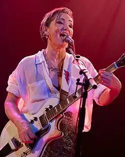 A photograph of Tunstall smiling, looking away from the camera. A microphone is positioned in front of her face.