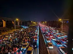 Hundreds of bikers at night lines up on the highway and heavy traffic on the other side of the road