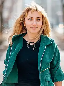 Professional photo of a blonde woman in a casual jacket walking down a forested street