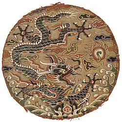 Roundel with dragon design. China, Qing-dynasty, late 17th century. Peacock feather barbules are used to highlight the dragon's scales.