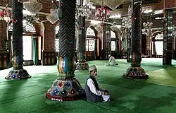 The mosque's interior has intricate woodwork and is richly decorated with papier-maché, seen above in 2007; the wooden structure makes it prone to fires, the latest such incident occurring in 2017