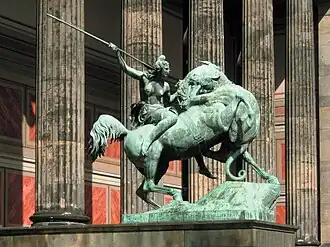 Sculpture of a nude, spear-wielding woman atop a horse. A big cat (panther or lion) attacks the horse.