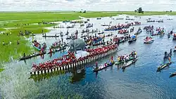 The Nalikwanda (a large canoe-looking boat with a model elephant on top and dozens of paddlers) travels down the Zambezi surrounded by canoes.