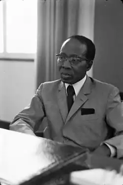 A black and white photograph of man sitting in the chair wearing suit
