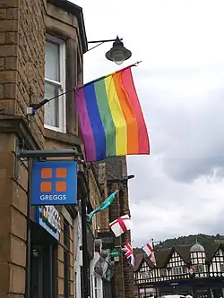 Pride flag flying with St George's Cross and Union Jack outside of Greggs