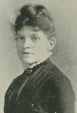 B&W portrait photo of a middle-aged woman wearing a dark, high-collared blouse with her hair in an up-do.