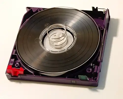 LTO-2 cartridge with the top shell removed, showing the internal components. Top right corner: tape access gate. Bottom left corner: write-protect-tab. Bottom right corner: cartridge memory chip