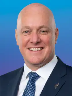 A smiling man wearing a dark business suit and tie