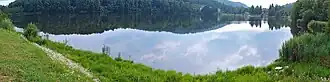A panoramic view of a body of water surrounded by green grass.
